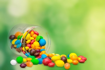 Colorful candies sweets falling out of a glass jar, composition isolated over the white background