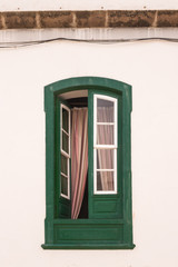 White wall with a green framed opened window