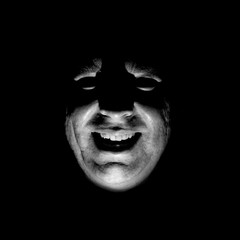 Stylish portrait of adult caucasian man. He smiles like maniac and seems like maniac or crazy. Black and white shot, low-key lighting. Angry man, fear concept. Isolated on black.