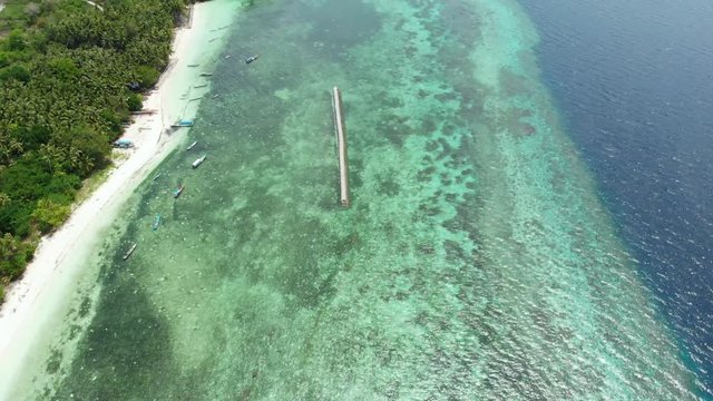 Aerial: Flying over tropical beach turquoise water coral reef , Tomia island Wakatobi National Park Indonesia Maldives Polynesia white sand beach