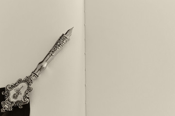 Old feather pen and empty sheet of paper. Back drop background. View from above. Black and white