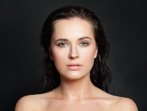 Beautiful young model woman with wet skin and hair on black. Female face closeup