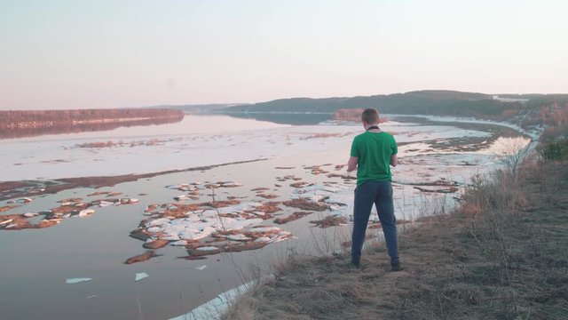 Young caucasian man taking pictures of great river with pieces of ice