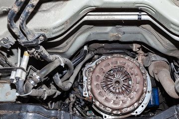 View of the car's clutch basket during the repair of a car lifted on a lift in a vehicle maintenance workshop. Industry in the auto service.