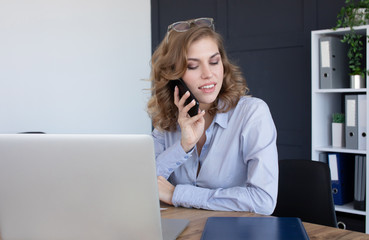 Concentrated young beautiful businesswoman working on laptop in bright modern office