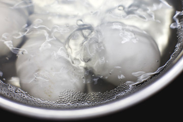 chicken eggs boil in water.  eggs are cooked in a saucepan on the stove.