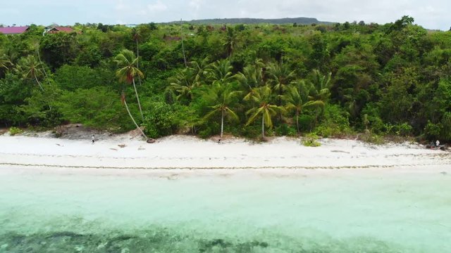 Aerial: Flying over tropical beach turquoise water coral reef , Tomia island Wakatobi National Park Indonesia Maldives Polynesia white sand beach
