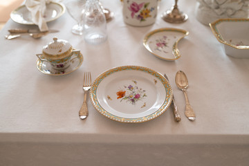 Obraz na płótnie Canvas Wedding table decoration with expensive retro royal majesty porcelain service plates and cutlery in a palace