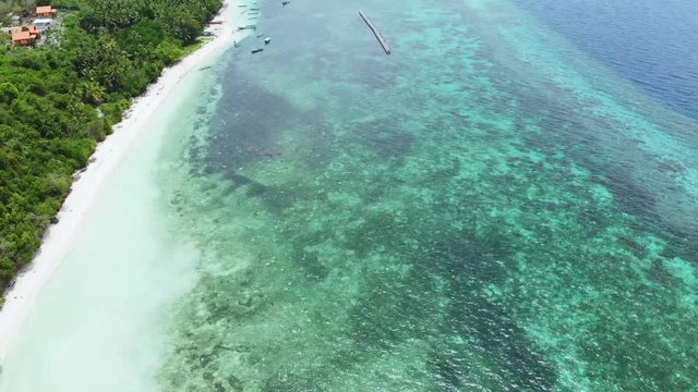 Aerial: Flying over tropical beach turquoise water coral reef , Tomia island Wakatobi National Park Indonesia Maldives Polynesia white sand beach