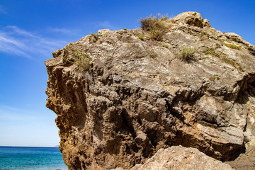 rock in the foreground with beach and blue sky in the background