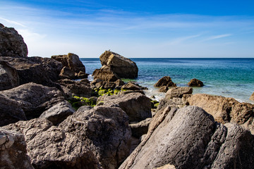 rocks with beach in background and sky blue and white