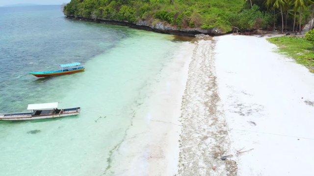 Aerial: Flying over tropical beach turquoise water coral reef , Tomia island Wakatobi National Park Indonesia Maldives Polynesia white sand beach