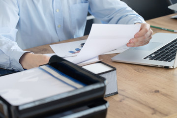 Fototapeta premium Close up of male hands with laptop computer, papers in business office 