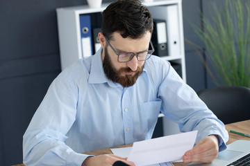 Portrait of young man sitting at his desk in the office