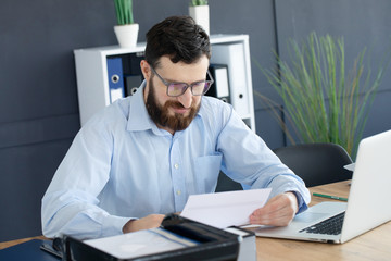 Portrait of young man sitting at his desk in the office