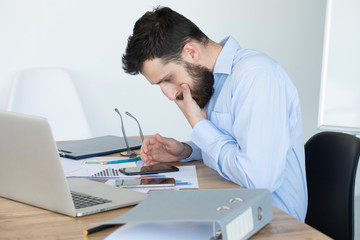 Portrait of young man sitting at his desk in the office