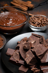 Melted chocolate or Hazelnut spread in glass bowl and chocolate pieces on dark concrete background