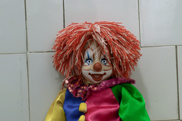 Creepy clown sitting near the wall