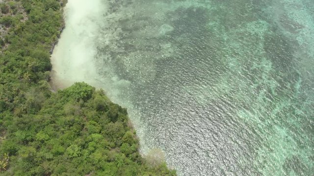 Aerial: Flying over tropical beach turquoise water coral reef , Tomia island Wakatobi National Park Indonesia Maldives Polynesia white sand beach. Native cinelike D-log color profile