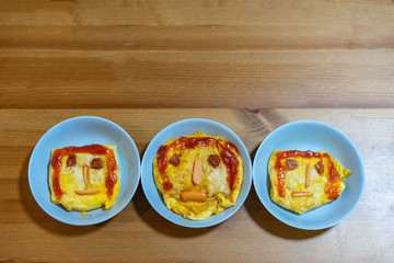 the happy face on the yellow fried egg in blue dish on the wood table.