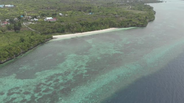 Aerial: Flying over tropical beach turquoise water coral reef , Tomia island Wakatobi National Park Indonesia Maldives Polynesia white sand beach. Native cinelike D-log color profile