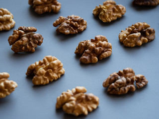 Row of walnuts on gray and blue textured background with a copyspace; Top view of kernel halves; close up food photo from above; snack and nutrition, vitamins and minerals;