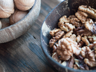 Walnuts in the cap on wooden background with copy space; coconut bowls with nuts; a healthy diet in eco-friendly dishes; nutrition and snack for busy people; ingridient for dishes and cooking