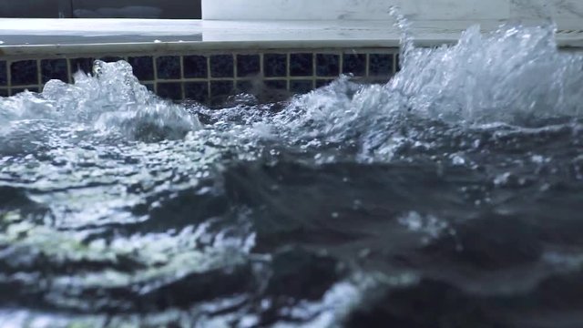 Splashing water in jacuzzi pool on spa center. Boiling water in jacuzzi tub in luxury spa resort hotel. Hydrotherapy and hydromassage concept.