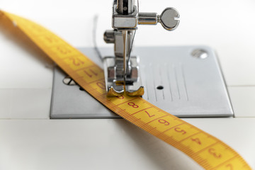 close-up sewing machine and yellow measuring tape