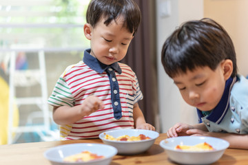 The brothers are enjoying their favorite omelet before going to school.