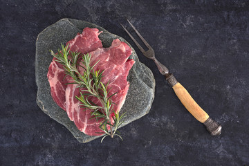 Raw meat steak on dark background. Copy space text concept. Fresh rosemary.