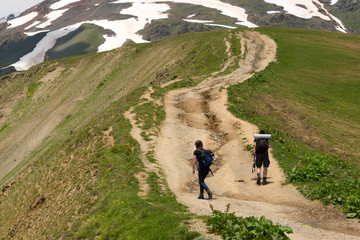 Mestia, Georgia - Jun 25 2018: Tourists with hiking backpacks on Hiking trail leading from Mestia to Koruldi lakes. a famous landscape in Mestia, Samegrelo-Zemo Svaneti, Georgia.