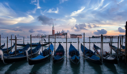 A row of gondolas parking beside the San Marco Place at sunrise with the curch San Giorgio di Maggiore in the background in Venice, Italy