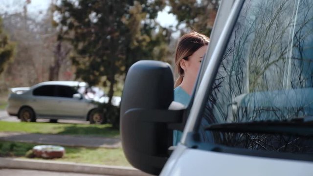 A young, graceful girl in a medical uniform, sits in the cab of an ambulance to go to the aid of the patient.