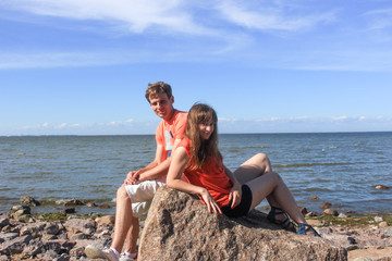A couple of lovers sitting on boulders by the sea