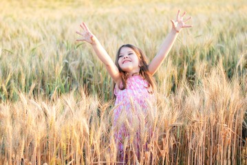 Beautiful little caucasian girl on a wheat field with ripe golden spike and sun backlit. Long...