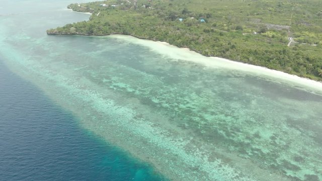 Aerial: Flying over tropical beach turquoise water coral reef , Tomia island Wakatobi National Park Indonesia Maldives Polynesia white sand beach. Native cinelike D-log color profile
