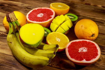 Assortment of tropical fruits on wooden table. Still life with bananas, mango, oranges, grapefruit and kiwi fruits