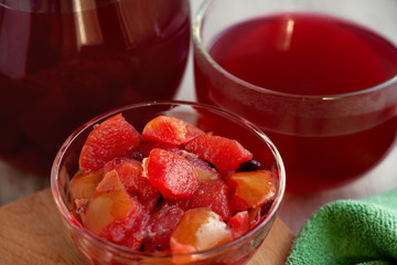 Juice from boiled fruits and berries. Healthy food in the form of fruit and berries compote. Chopped boiled fruits and berries in a bowl and juice in a glass container.