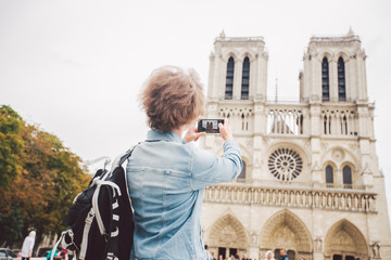 Tourist in Paris making funny selfie near Notre Dame Cathedral. Beautiful young Caucasian tourist...