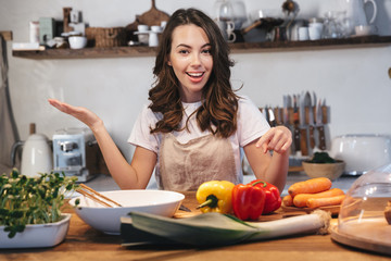 Beautiful young woman wearing apron cooking vegetables