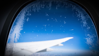 The porthole of a passenger plane covered with a layer of ice.