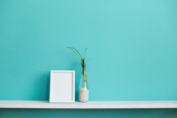 Modern room decoration with Picture frame mockup. White shelf against pastel turquoise wall with...
