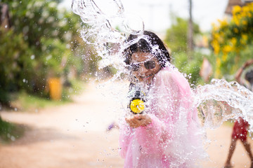 Young happy beauty Asian girl with water gun wearing summer shirt in Songkran festival - water...
