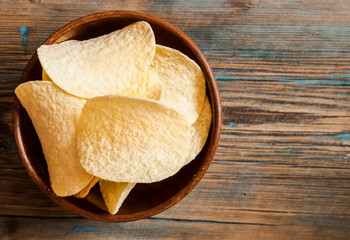 Crispy potato chips in wooden bowl. Salted potato chips.