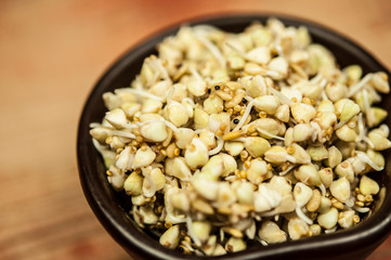 Buckwheat in a wooden bowl on an old wooden table, closeup view