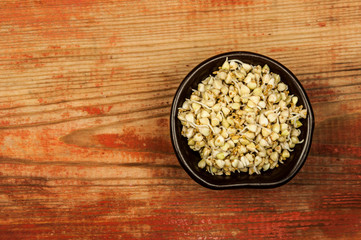 Buckwheat in a wooden bowl on an old wooden table, closeup view