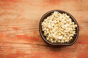 Buckwheat in a wooden bowl on an old wooden table, closeup view