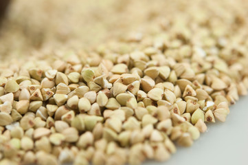 Raw green buckwheat pile on white background. Vegan or vegetarian food