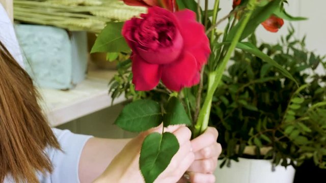 Female florist in flower shop. Woman making a beautiful and stylish bouquet of fresh flowers in floral design studio. 4K